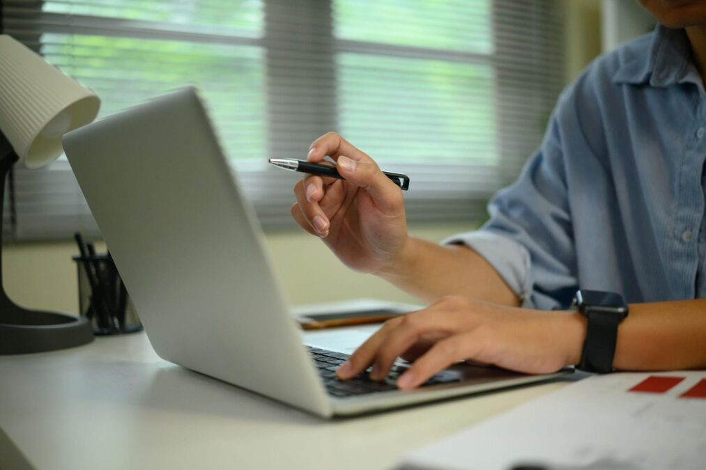 pessoa apontando uma caneta para notebook